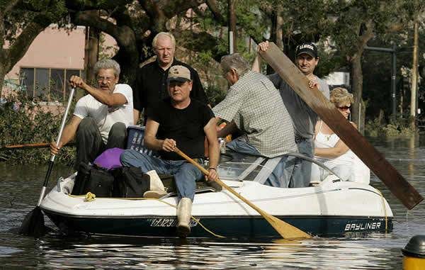 People on Canal Street in New Orleans move to higher ground. Tens of people have been killed by flooding, while thousands of residents have been left homeless