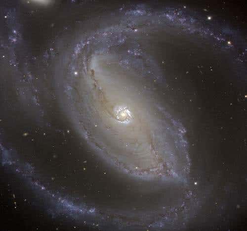 Astronomers imaged dim spiral arms of matter (red) at the centre of galaxy NGC 1097 