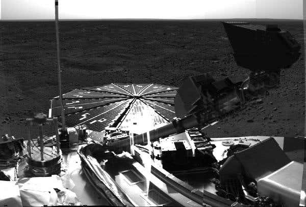 The robotic arm on Phoenix salutes the Martian landscape, with the scoop appearing as a large dark shape just below the horizon and above the lander's deck 
