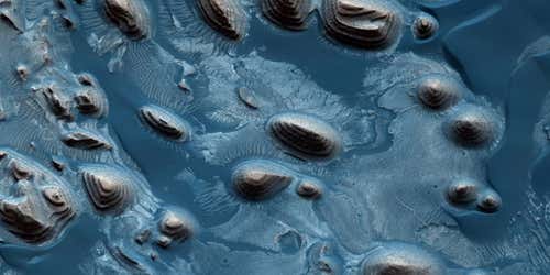 Erosional mounds inside a crater show rhythmic layering in this false-colour image 