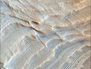 Two scales of stratification appear in this false-colour image of a crater called Becquerel. Each thin layer - measuring a few metres tall - may have been laid down during a 120,000-year cycle in which Mars tilts back and forth on its axis.  Those thin layers are bundled together in groups of 10, which probably correspond to modulations in the strength of the 120,000-year cycle over time 