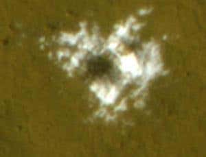 Formed sometime between January and September 2008, this fresh crater has dredged up barely buried water ice and splashed it onto the Martian surface. The HiRISE camera aboard NASA's Mars Reconnaissance Orbiter recorded this colour close-up image on 1 November 2008. The scene is about 30 metres across.