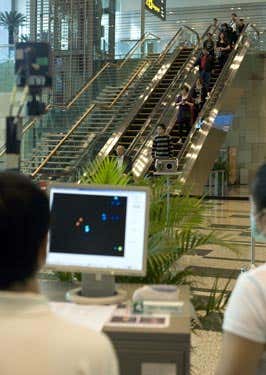 Health screening officers watch a thermal scanner at Changi Airport Terminal 3 in Singapore
