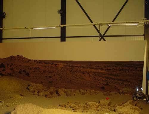 The markers are lit up with reflected light in this image, which also captures three of the cameras, at the top of the frame