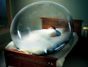 A person asleep in bed and enclosed in a big bubble