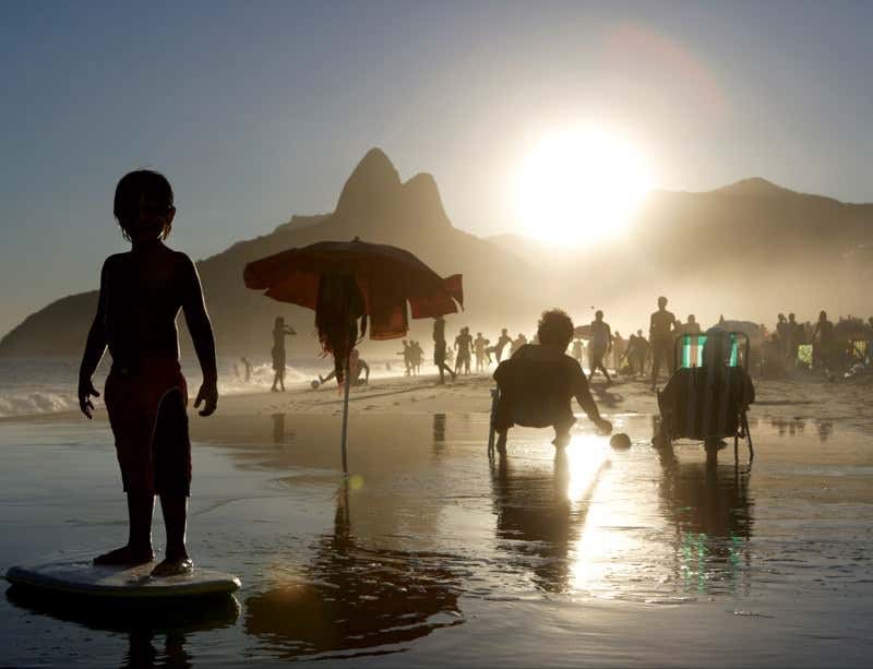 People on a beach in sihouette with a low sun behind