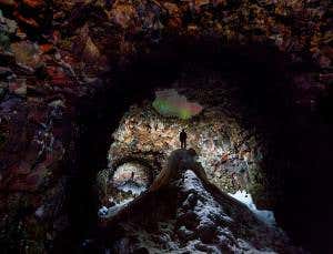 Frozen Icelandic cave illuminated by Northern Lights