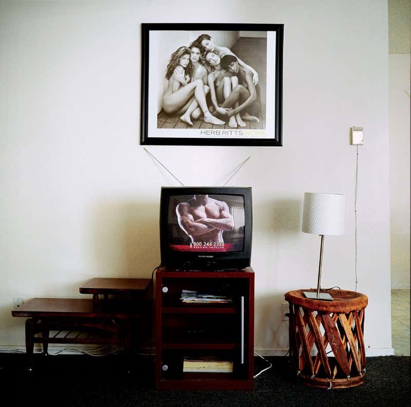 Herb Ritts framed black and white photograph of naked women hanging on a wall above a television showing a muscular man's torso
