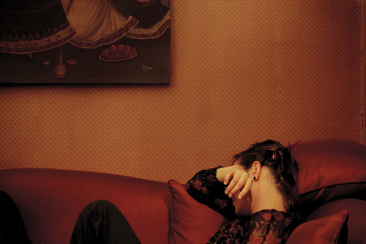 A woman lying on a sofa with her hand across her face