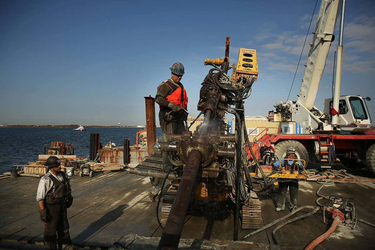Building a new sea wall in the Queens borough of New York City, one year after Hurricane Sandy devastated much of the area with severe flooding and wind damage. It's just a pic of some workers and construction equipment with sea visible in the background