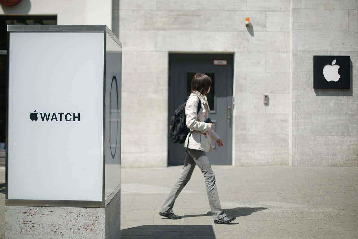 Person walking with Apple Watch logo in foreground and Apple logo in background