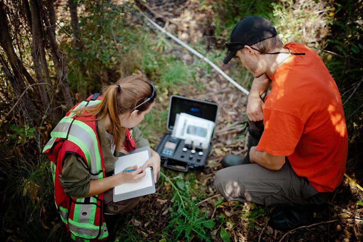 Two models pose as data collectors in a wood