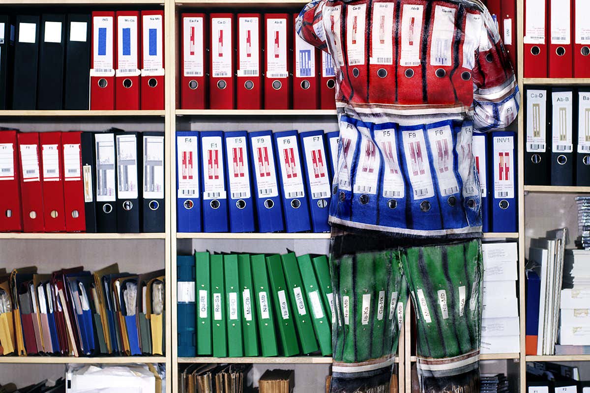 Outline of figure that is just visible over shelves of books