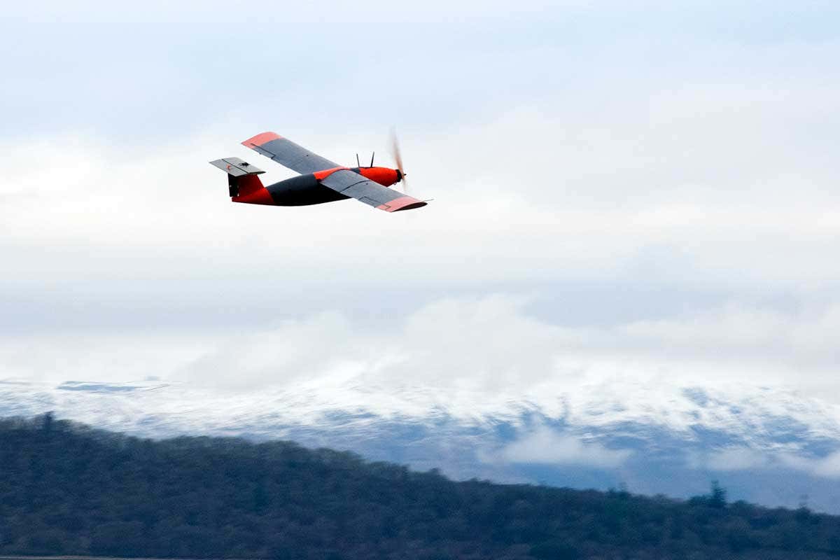Fixed-wing drone flying against a snowy backdrop