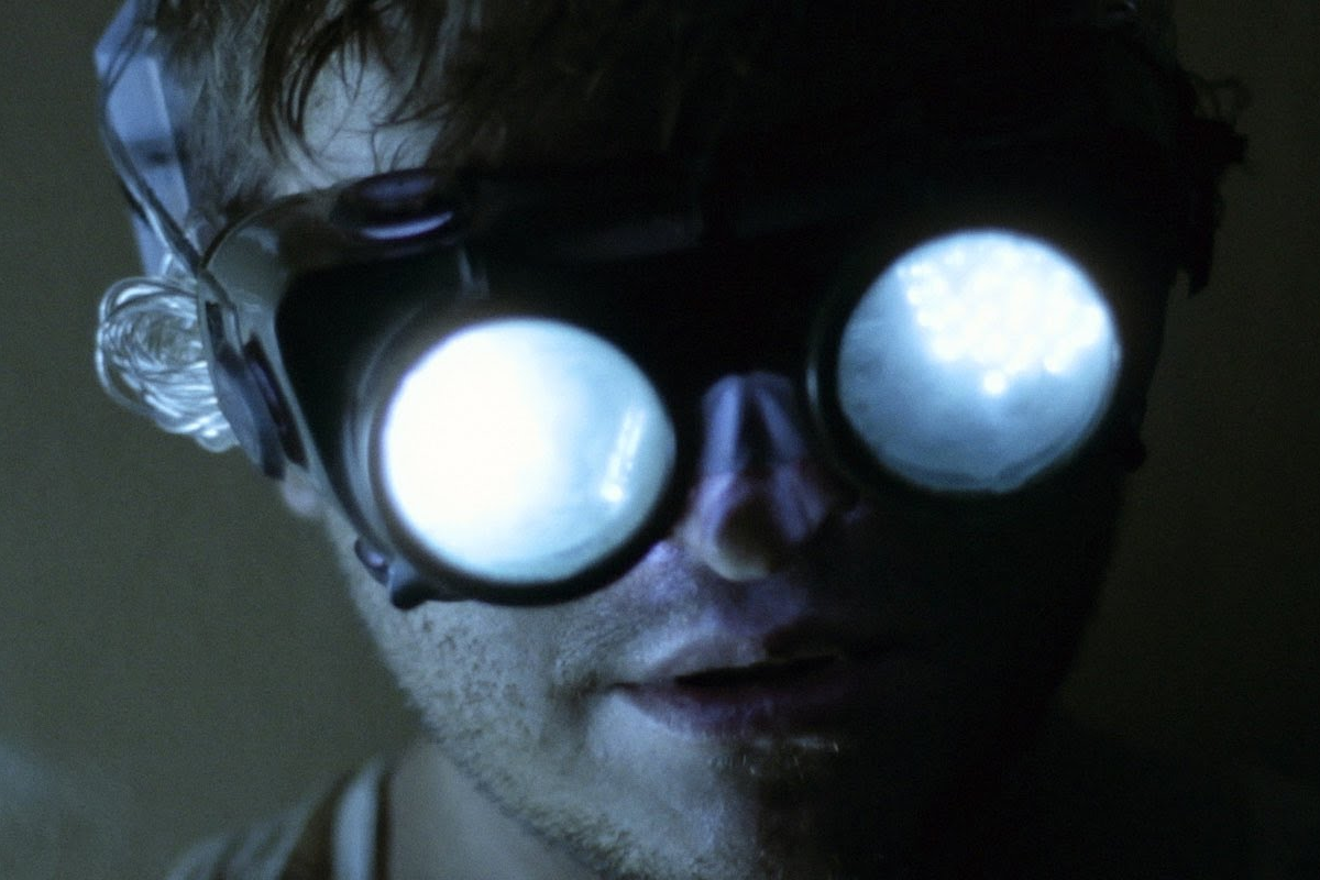 Dark blue image of man apparently wearing unusual goggles