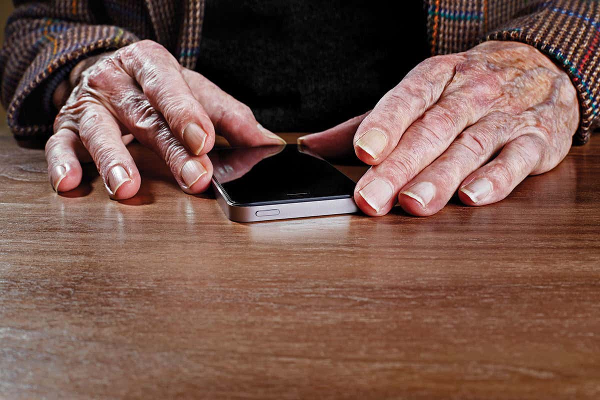 Old person's hands, with sleeves of tweed jacket, holding an iPhone