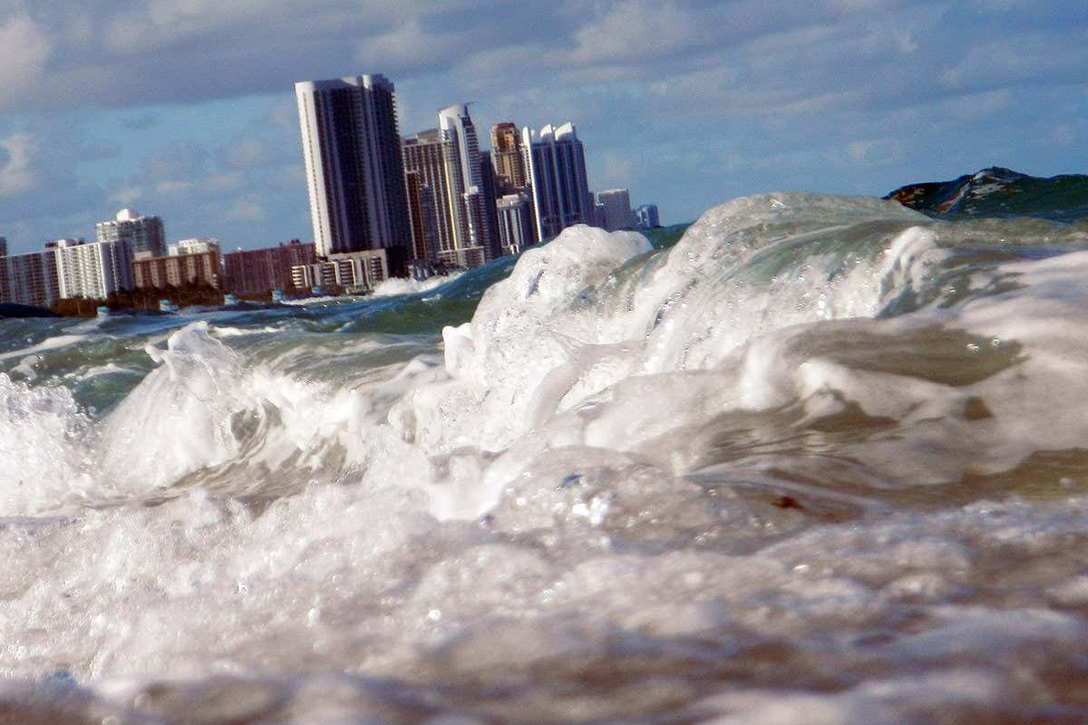 Big foamy waves rolling in, with Miami skyscrapers in the background
