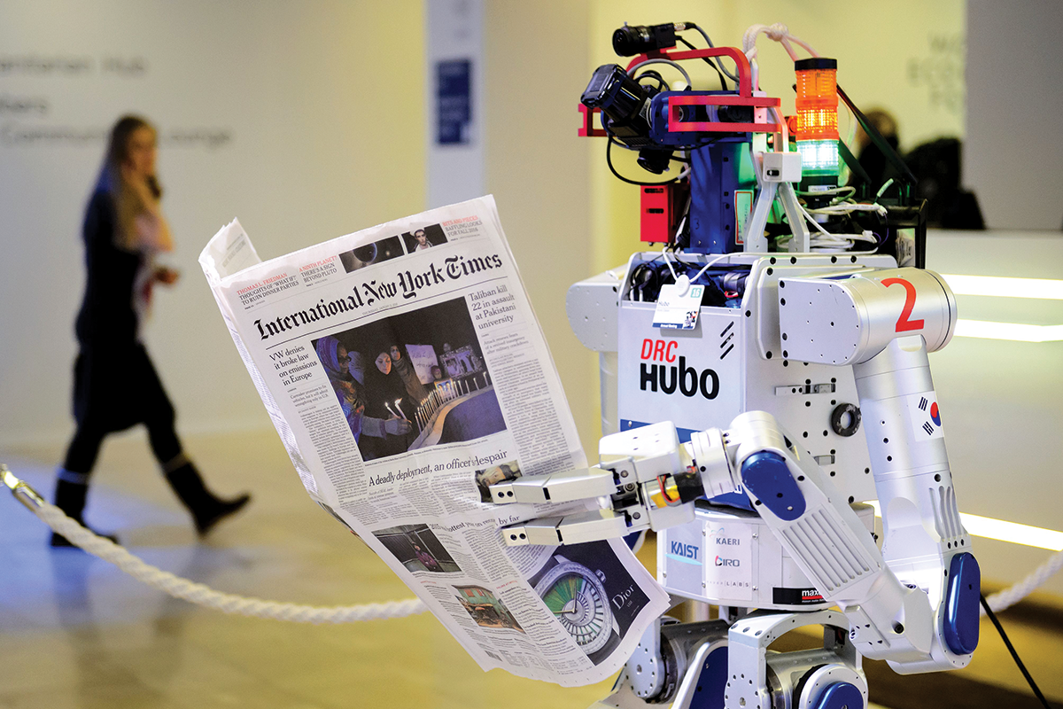 DRC Hubo robot holding a copy of the International New York Times newspaper