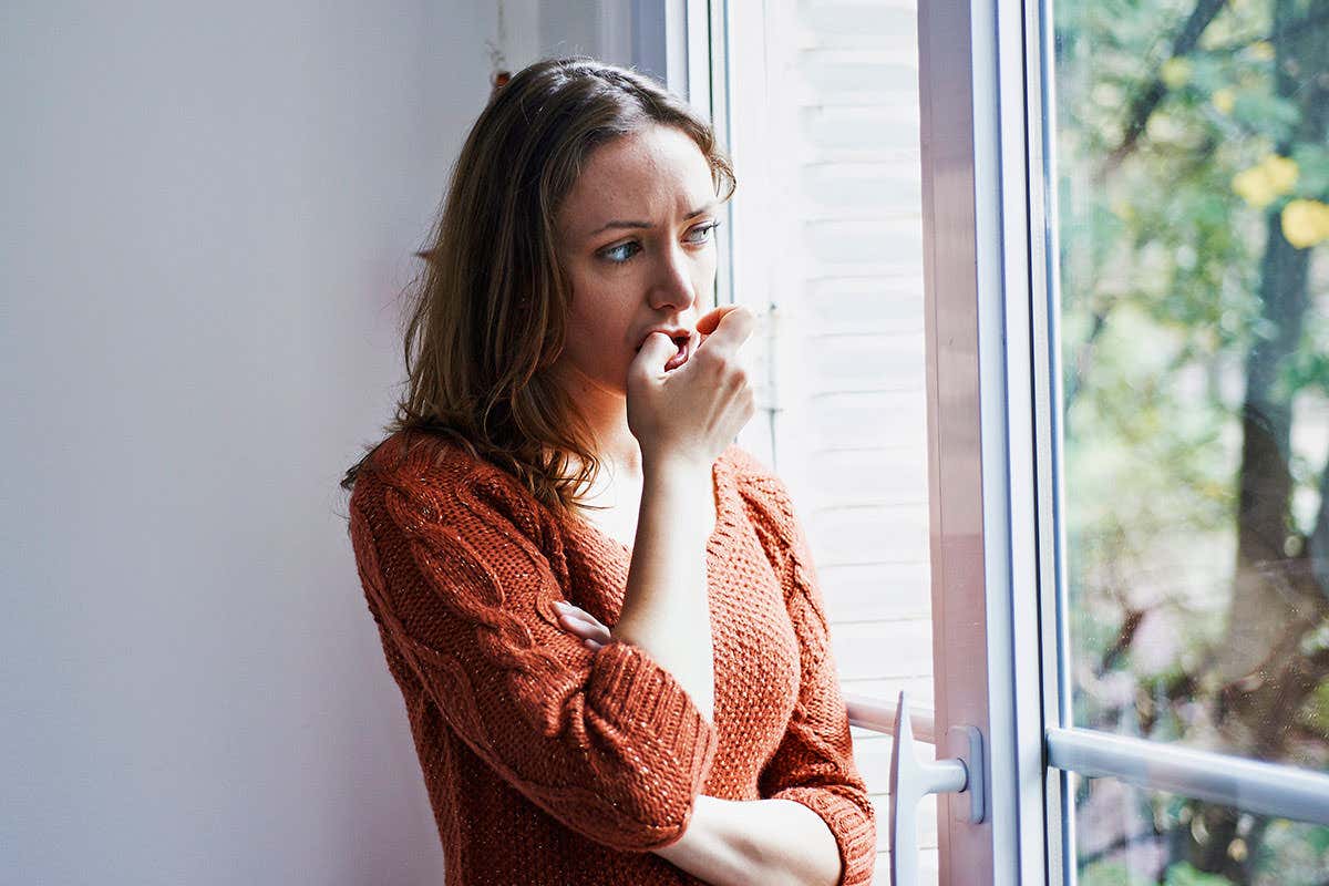 A woman looking anxious as she stands by a window