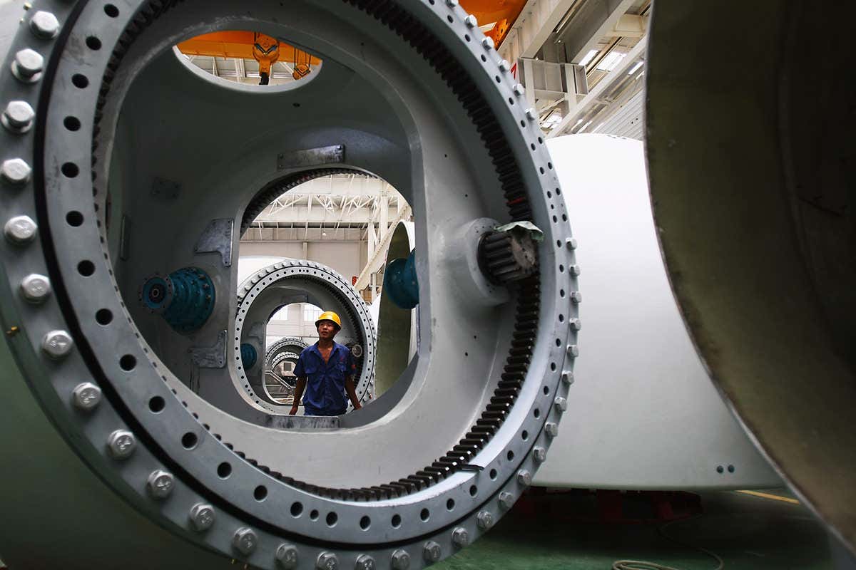 A worker looks at giant wind turbine parts