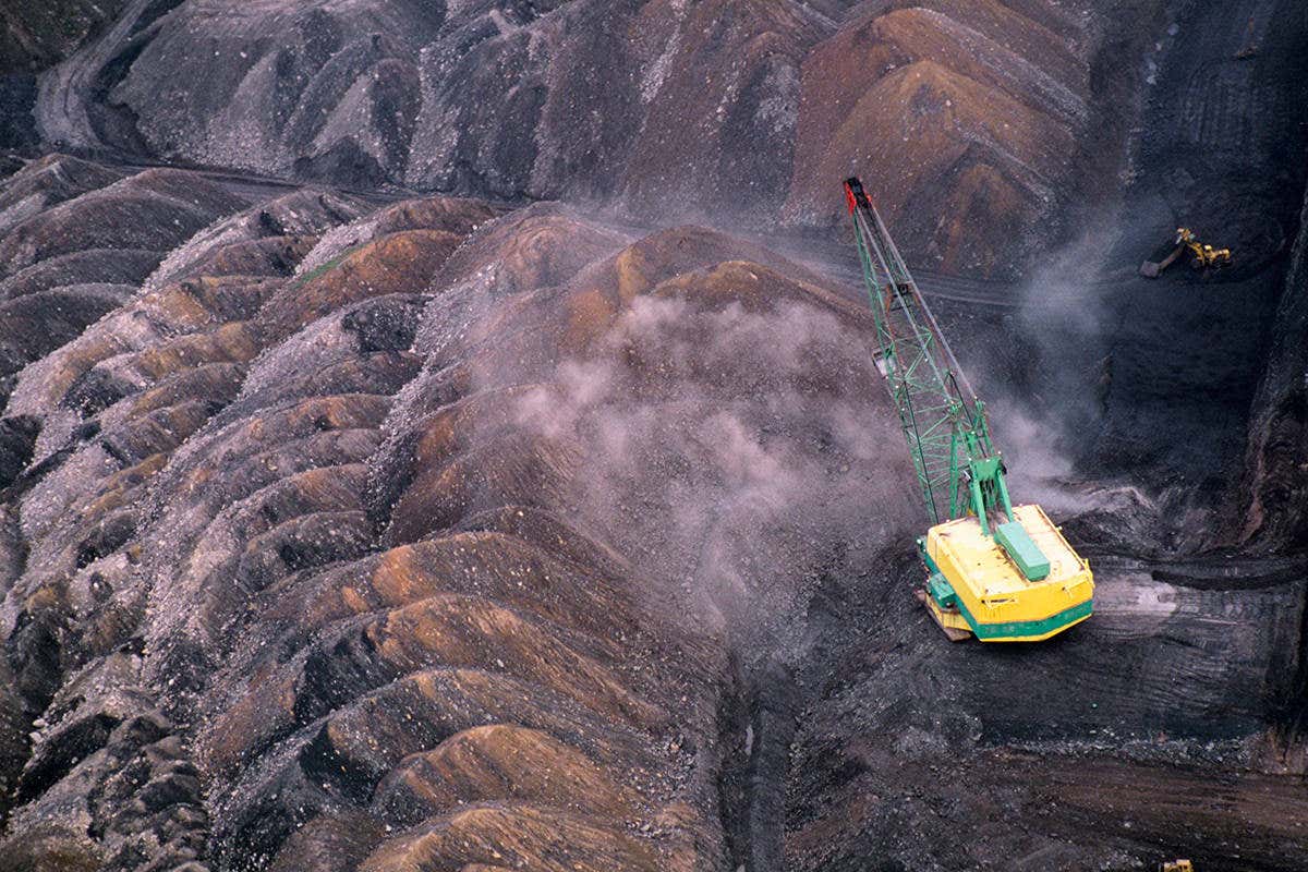 An open cast mine in Arizona - pic from above showing black earth and a bit of heavy plant machinery for scale