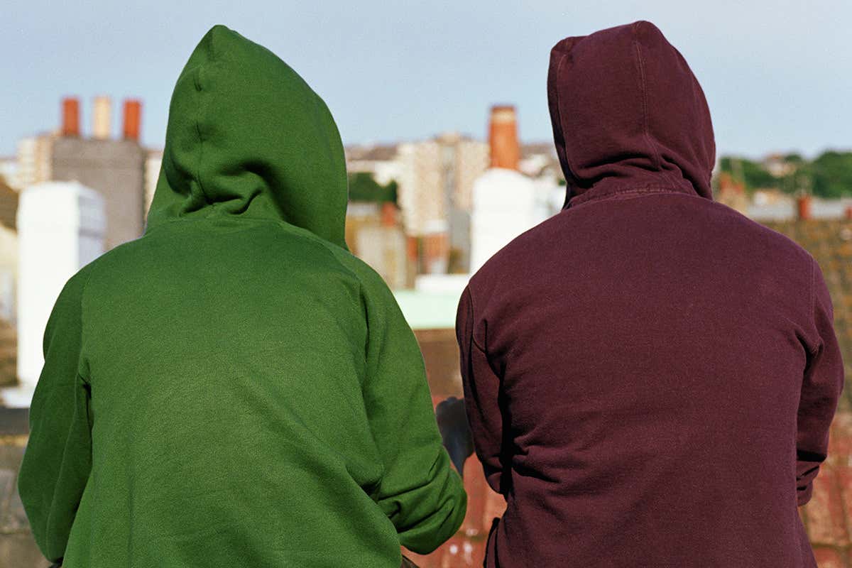 People wearing hoodies with their backs to the camera looking out over rooftops