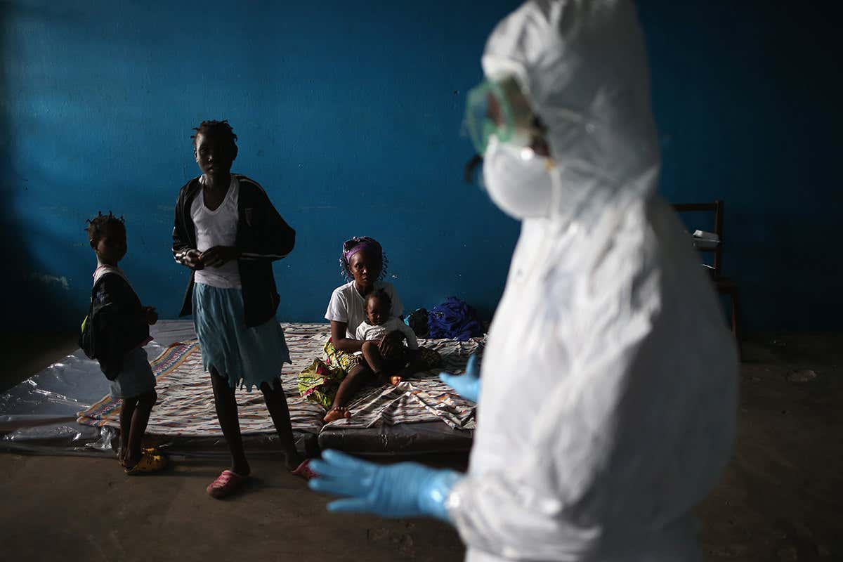 Masked health worker addresses people in makeshift isolation ward in Liberia