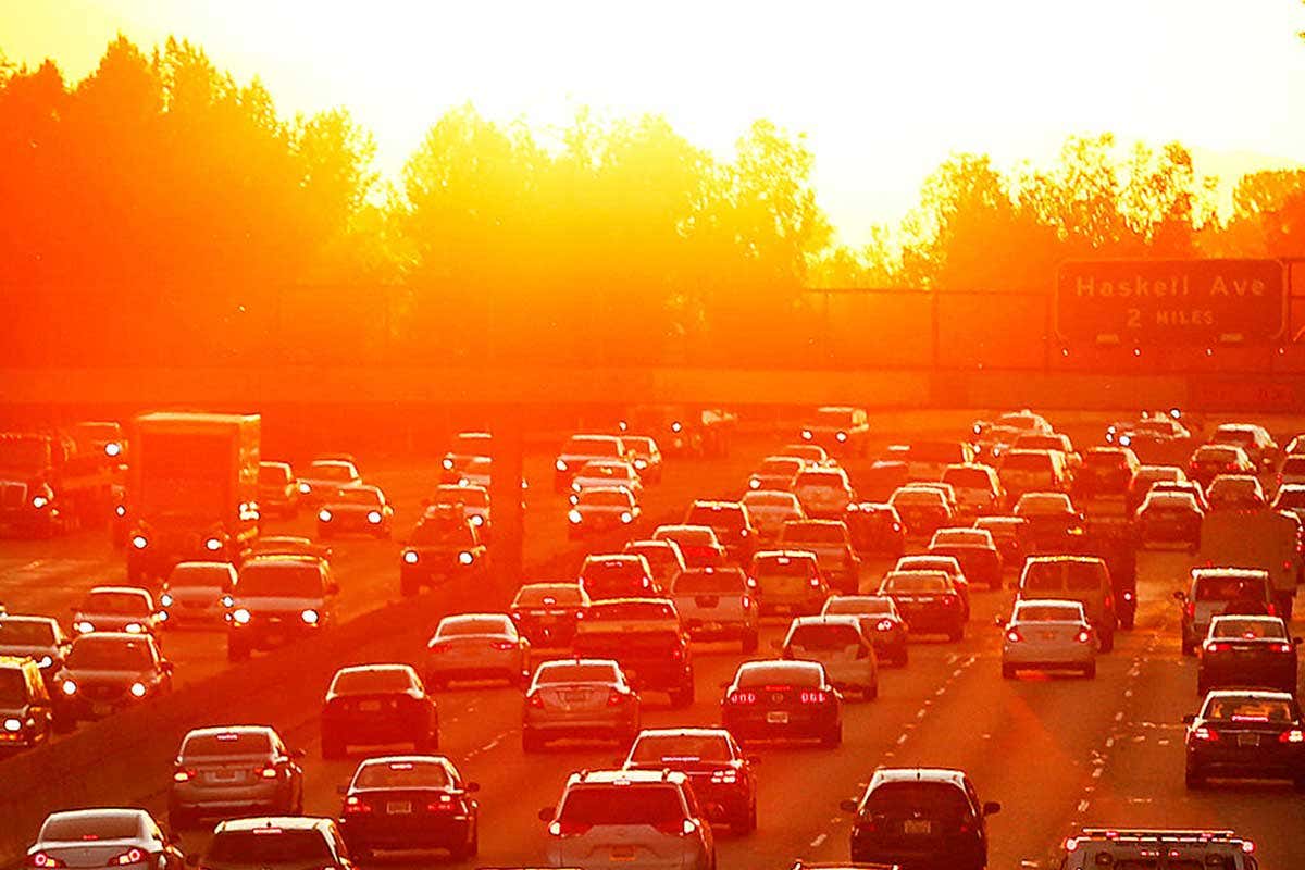 Jam of cars going both ways on a five-lane highway in LA, with the sun in the background making everything glow and giving an aura of hot, hot, hotness