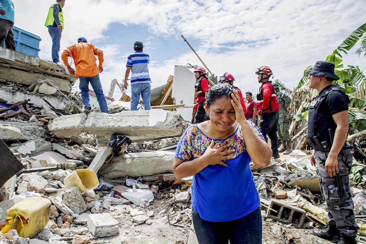 Woman sobs in front of rubble of destroyed building, Ecuador
