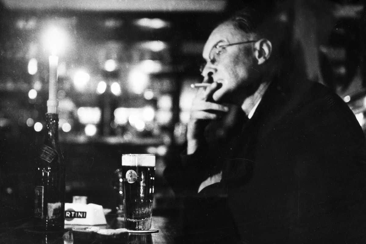 Older man smoking and drinking in a pub
