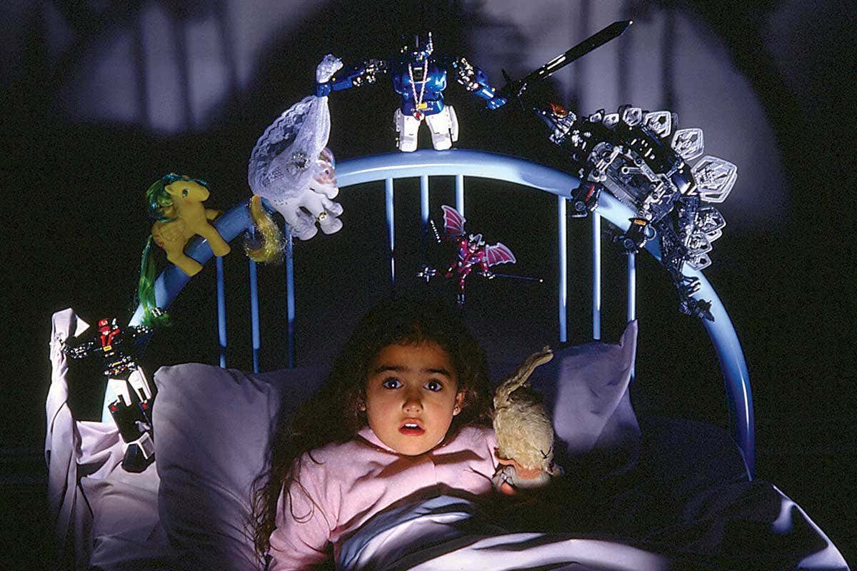 A girl in bed surrounded by scary toys