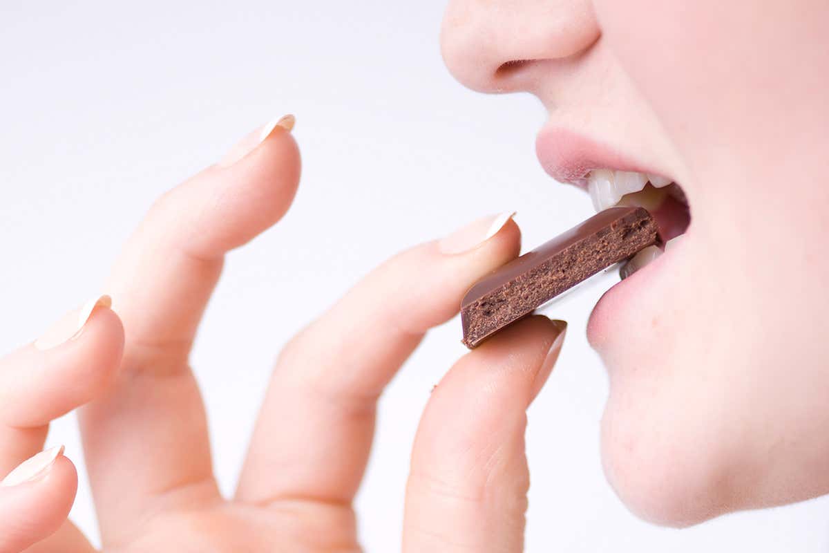 A person biting into a piece of chocolate