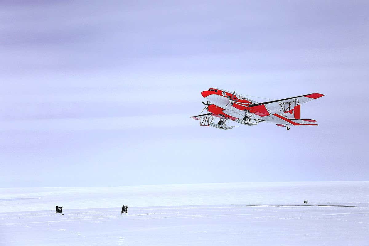 A plane flies over the icey Antarctic landscape