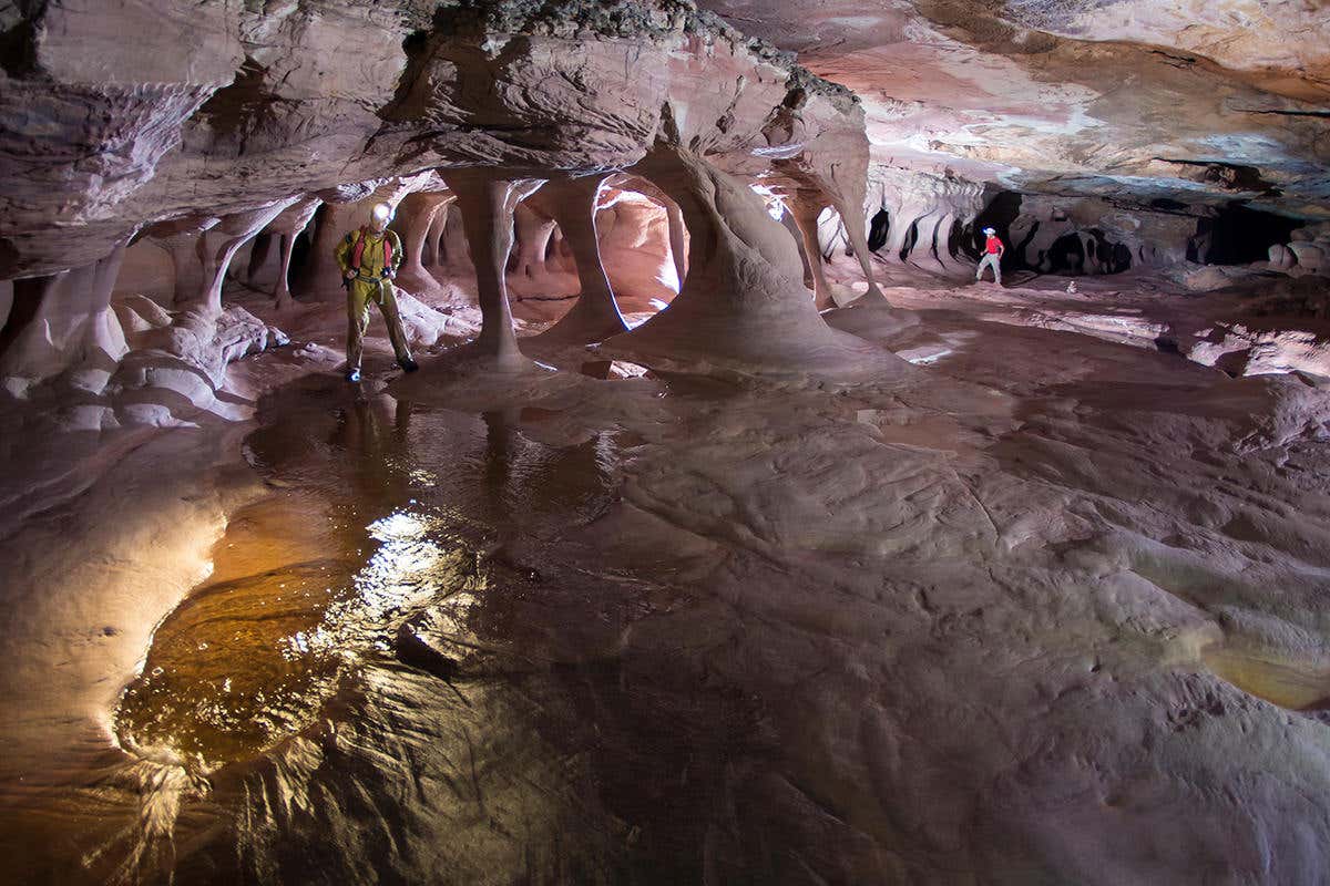 several columns of silica, reaching from floor to ceiling, within a large chamber of pinkish rock