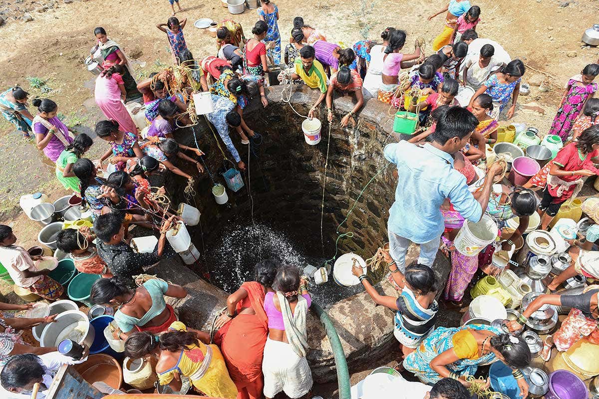Indian villagers throw containers attached to ropes into a well to collect their daily supply of potable water after a tanker made its daily delivery at Shahapur, some 130 km southwest of Mumbai, on May 13, 2016