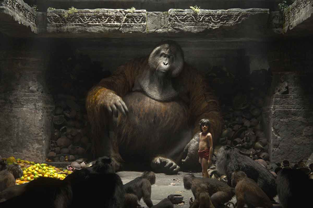 A still from the Jungle Book showing Mowgli standing with King Louie in a temple (which the ape fills) with smaller monkeys looking on