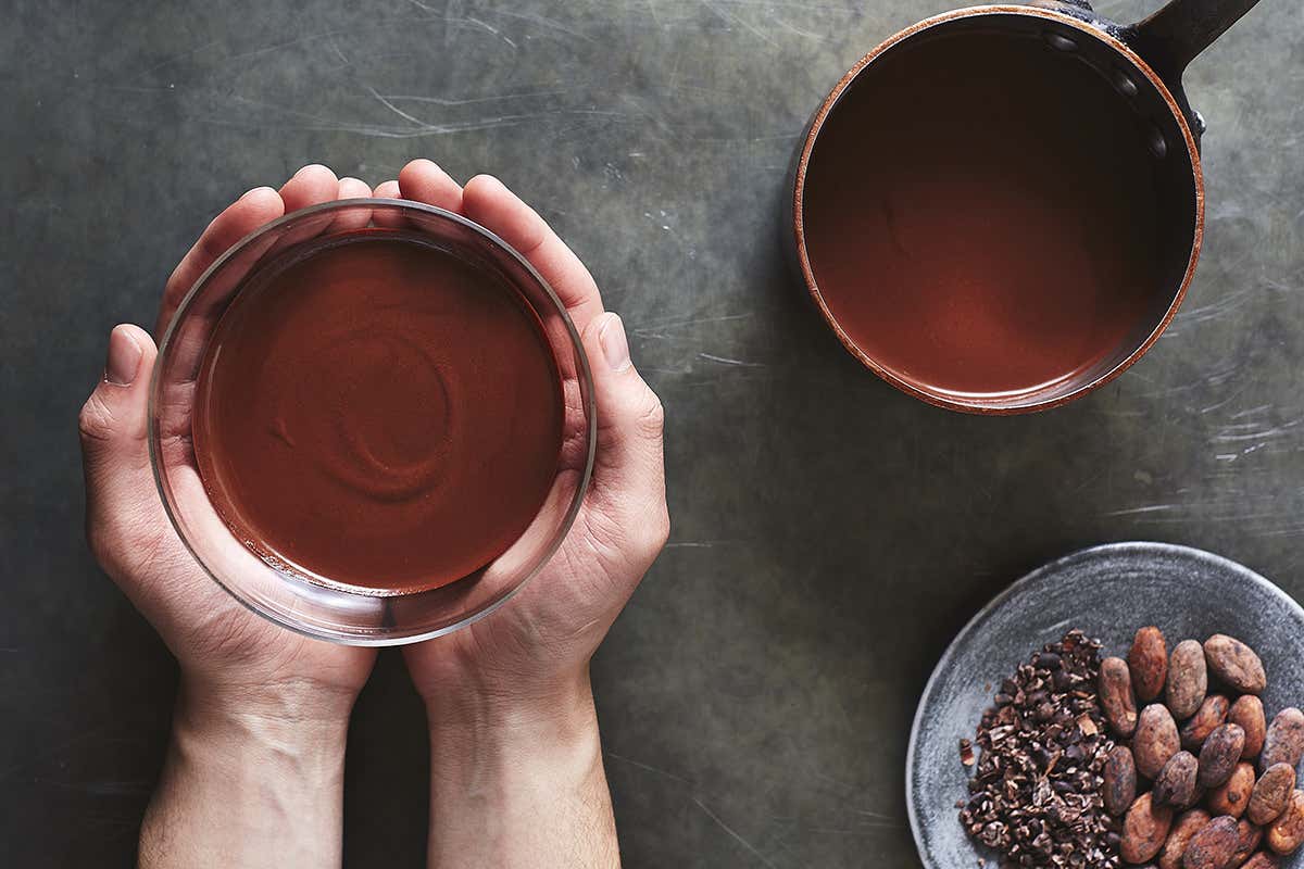 Someone holds a bowl of a cocoa drink