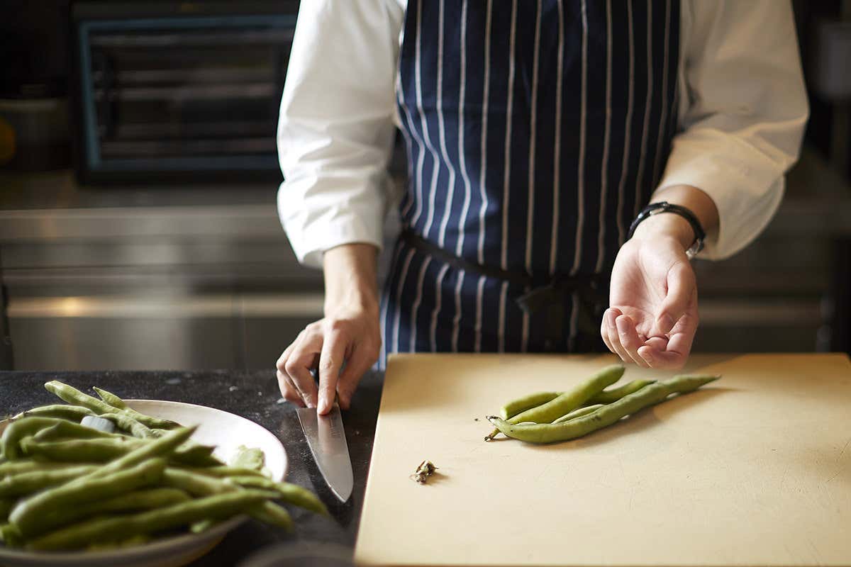 A chef chops broad beans on a chopping board