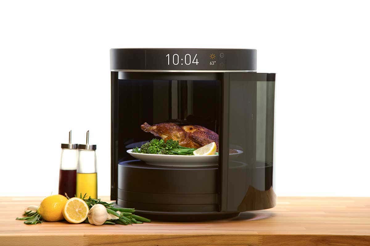 Drum-shaped Sage oven holding what looks like a roast chicken and some broccoli on one plate