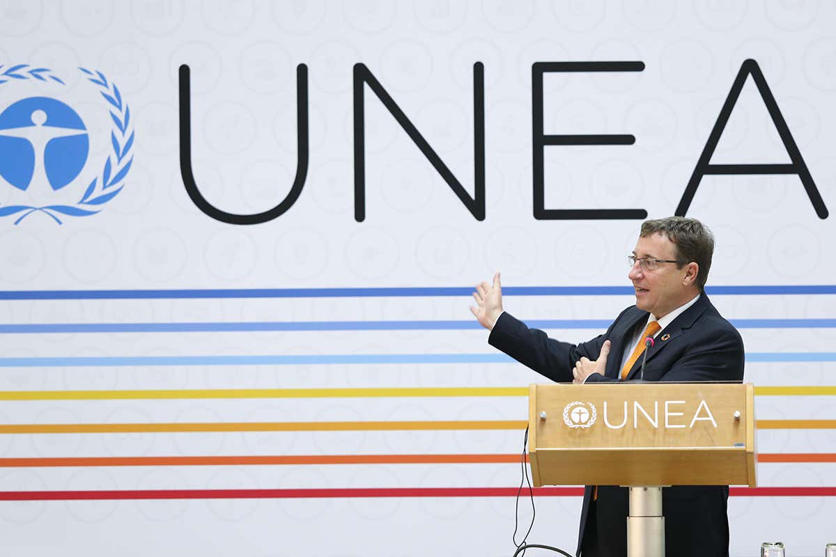 A speaker stand in front of a UNEA banner