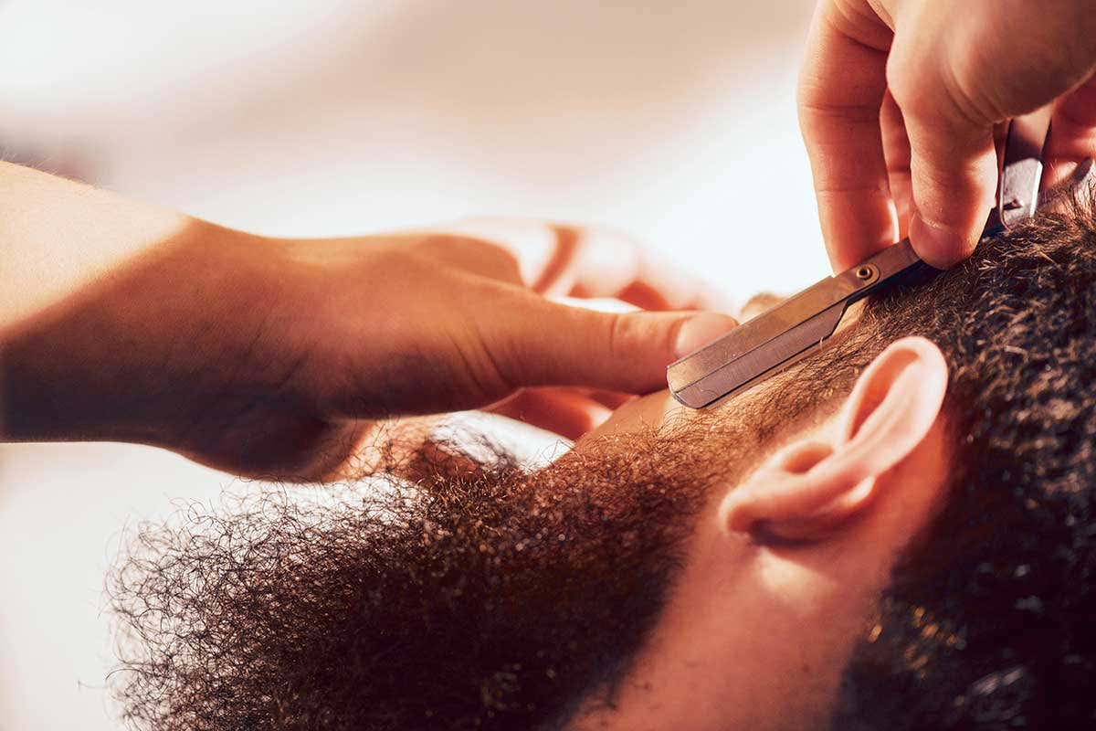 Man having black bushy beard shaved