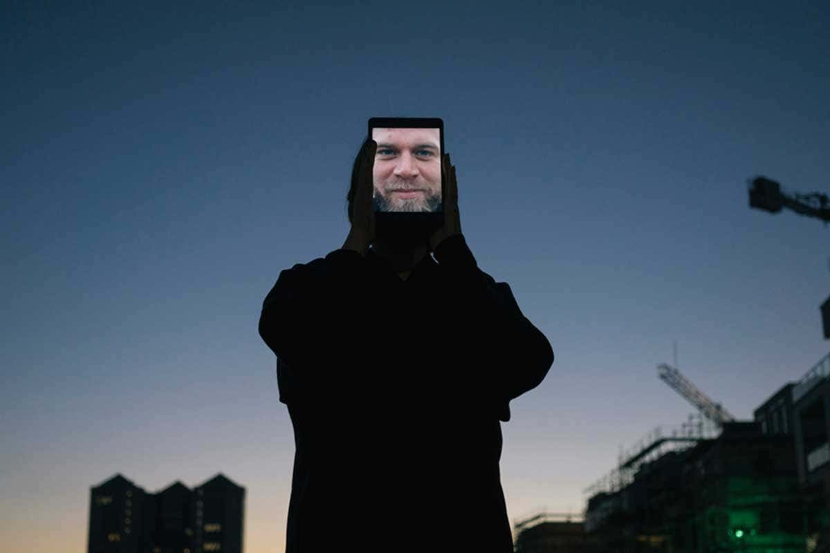 A cut out face of a man wearing black clothes