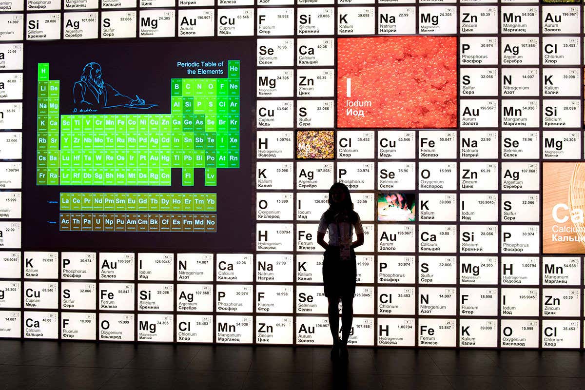 Personal silhouetted against big display of periodic table