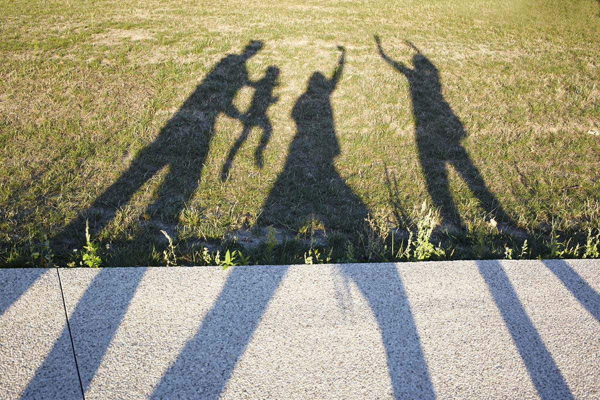Shadows on a grassy surface: three adults and a small child