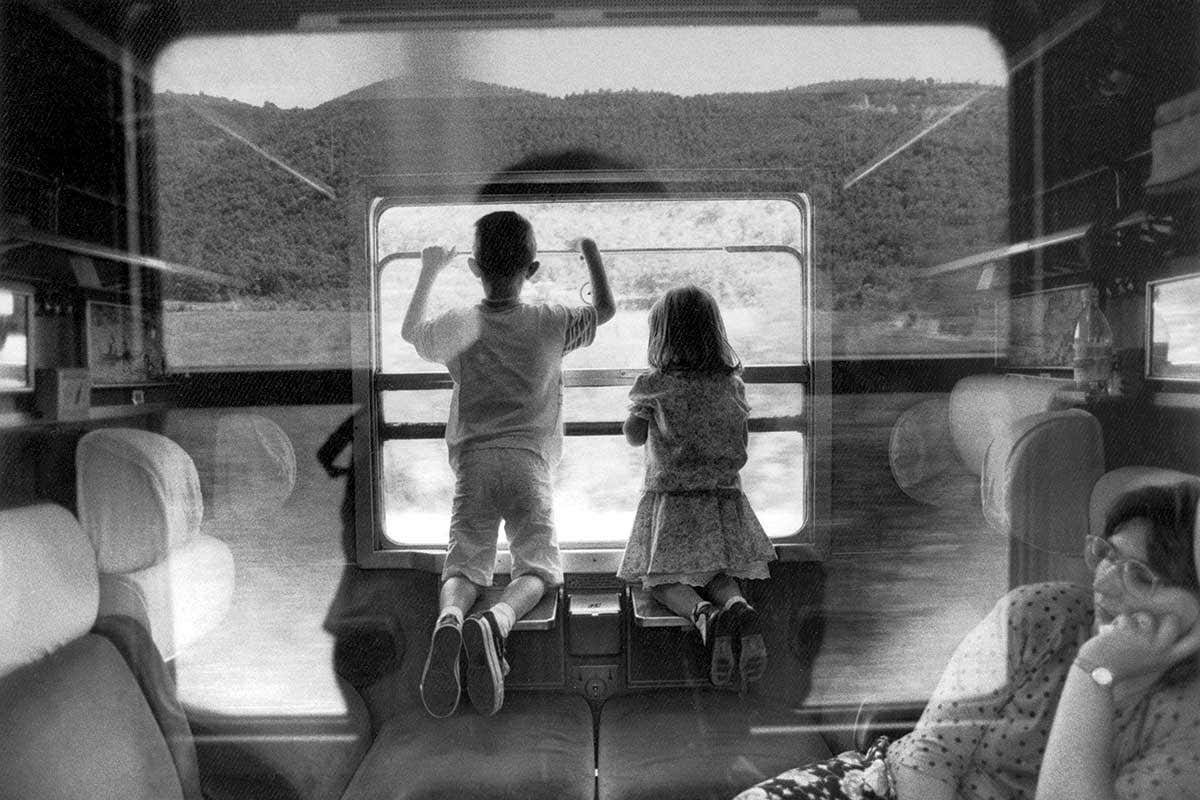 A boy and a girl looking out of a train window