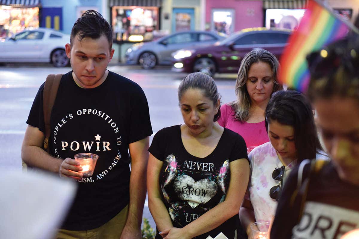 People holding candles and a rainbow flag