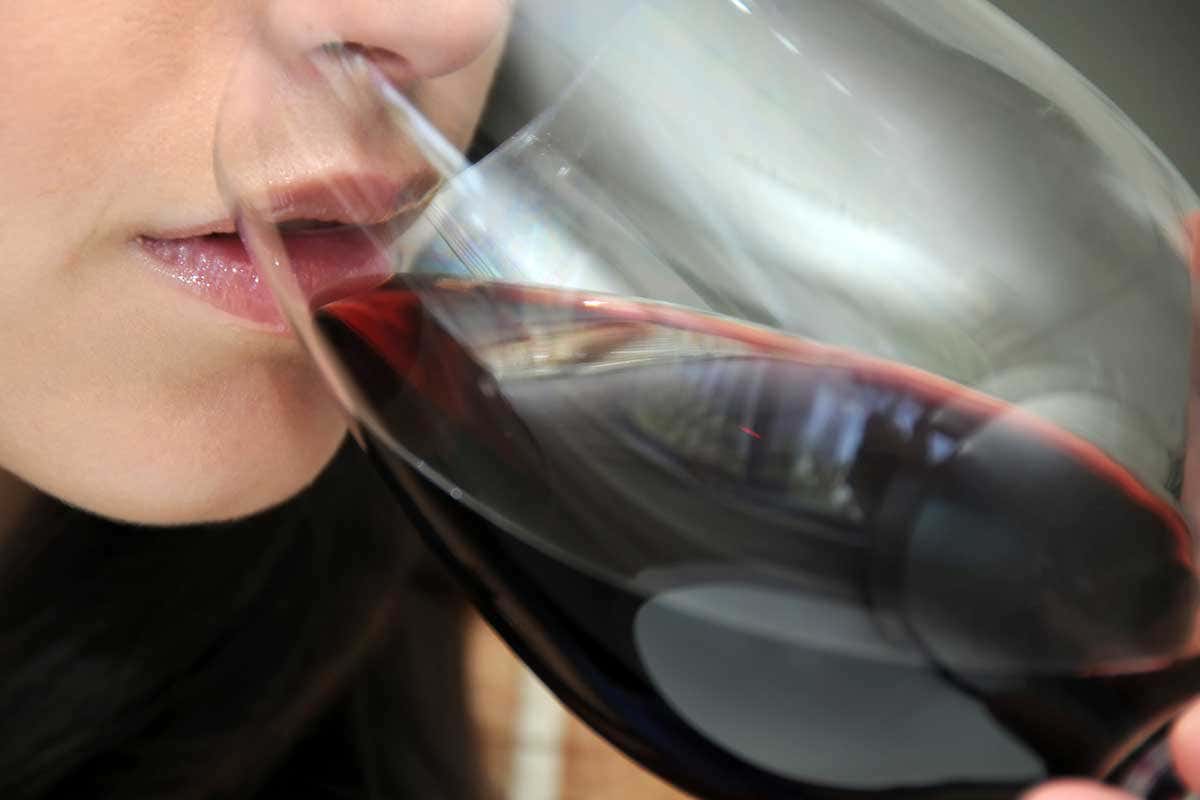Close-up of a woman sipping red wine from a large glass