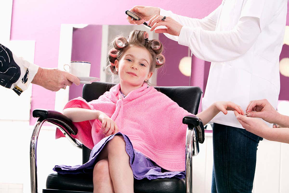 Child in curlers having manicure and hairdo