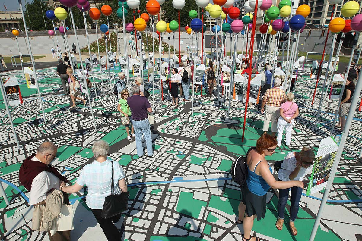 People walking on giant map of a city, with plenty of giant multicoloured pins marking important places