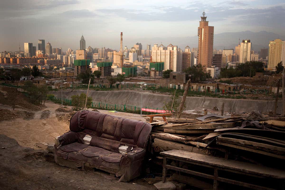 Dilapidated sofa in wasteland with tall city buildings in background